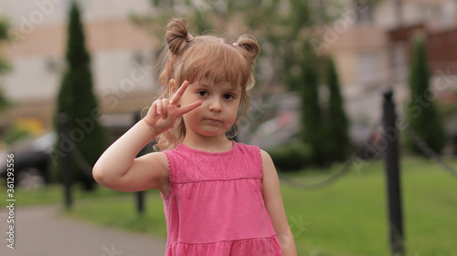 Little child girl against the blurred city street background. Cheerful, positive emotions, smile