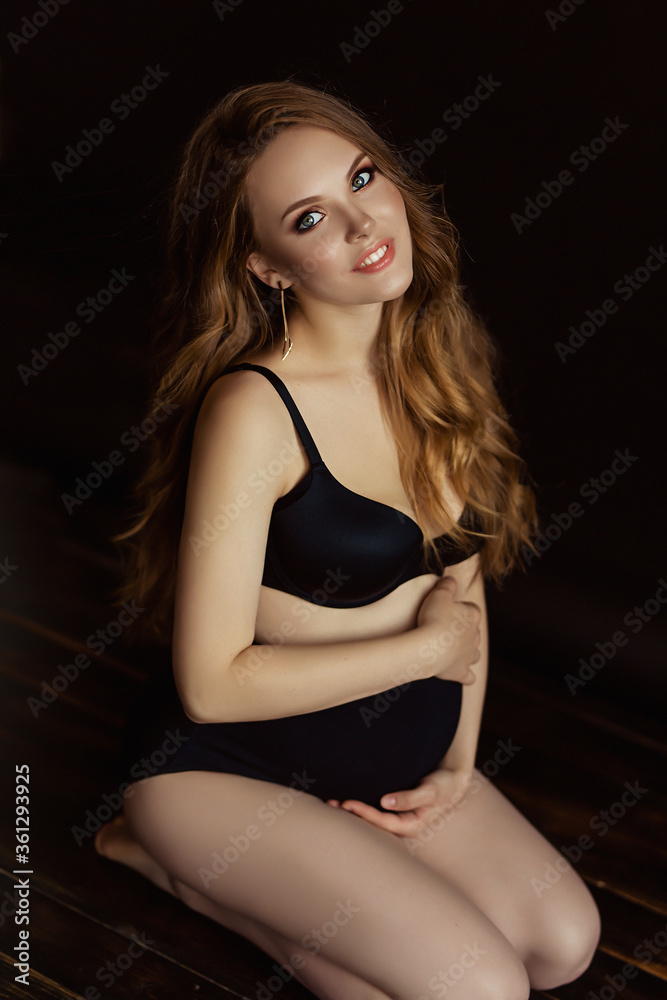 European pregnant woman with long hair in dark wear, happy future mother on black background, young future mom hugs her belly, beautiful wife expecting a baby European pregnant woman with long hair in dark wear, happy future mother on black background, young future mom hugs her belly, beautiful wife expecting a baby