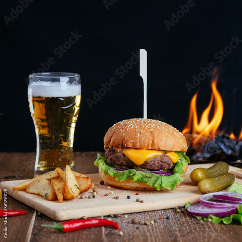 hamburger, fries and other snacks on a wooden board, square