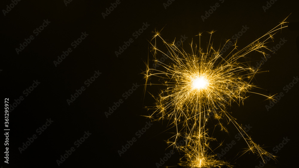 Happy New Year, colored sparkling burning sparkler or salute on a black background. Holiday concept, background