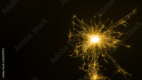 Happy New Year  colored sparkling burning sparkler or salute on a black background. Holiday concept  background