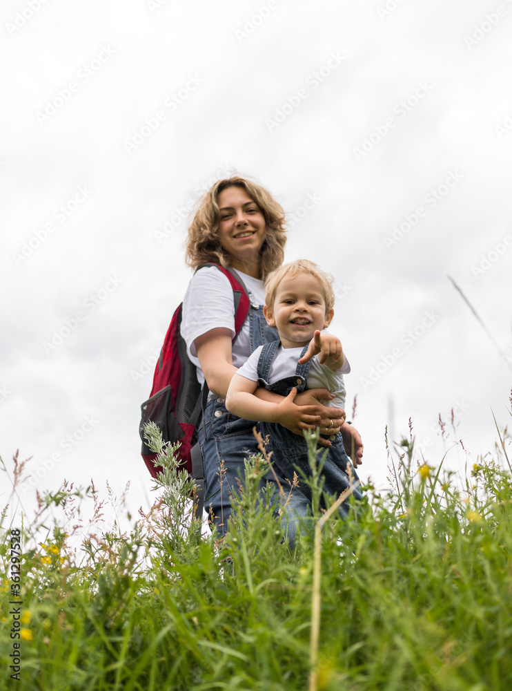 Fototapeta premium mom and her son walk in the park in identical denim jumpsuits. they enjoy time together and love each other. High quality photo