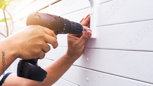 Home repair using a drill to drill on wooden wall cover