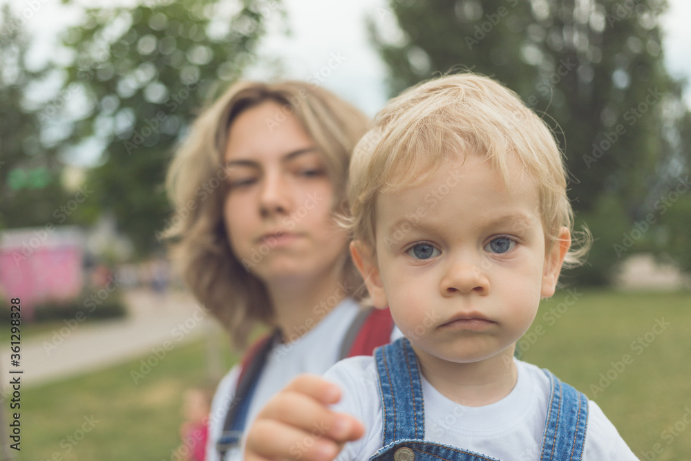 mom and her son walk in the park in identical denim jumpsuits. they enjoy time together and love each other. High quality photo mom and her son walk in the park in identical denim jumpsuits. they enjoy time together and love each other. High quality photo