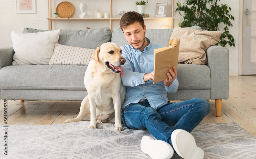 Guy holding book while smart pet reads it Guy holding book while smart pet reads it