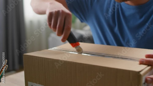 Close up shot as a young man opens a parcel with a knife