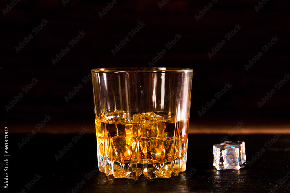 Whiskey drink on wooden table over dark background