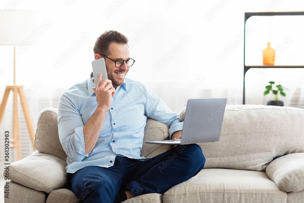 Portrait of successful smiling worker using cell phone and pc