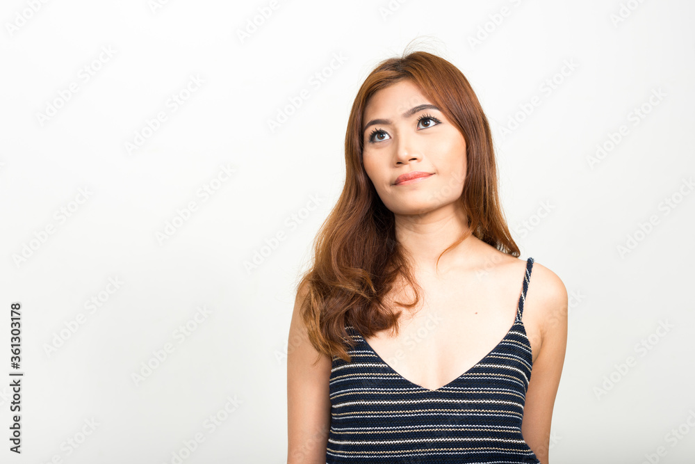 Portrait of young beautiful Asian woman thinking and looking up Portrait of young beautiful Asian woman thinking and looking up