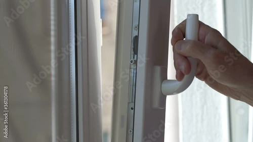 Wallpaper Mural aged person hand opens window holding white plastic handle against bright sunlight in summer slow motion close view Torontodigital.ca