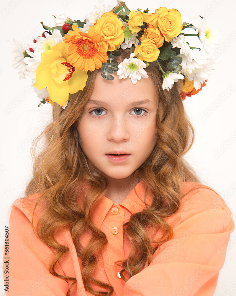 Studio photo of beautiful girl with luxurious locks hair, flower wreath on head. Fresh young skin, natural beauty. The material for article in blog, website, social network facial care, healthy food