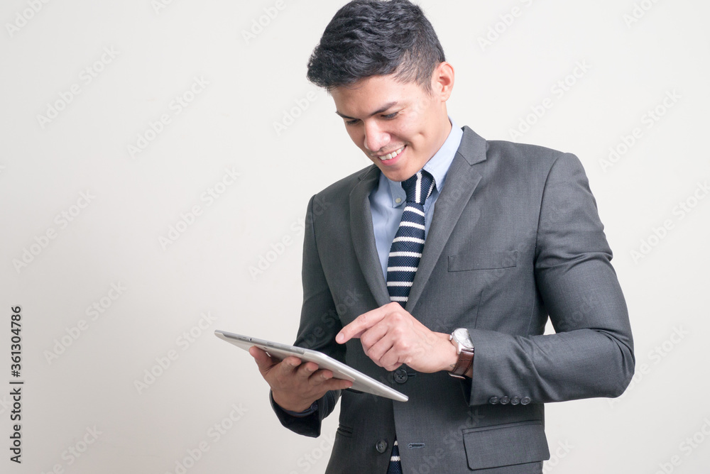 Portrait of happy young handsome Asian businessman using digital tablet Portrait of happy young handsome Asian businessman using digital tablet