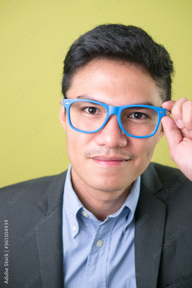 Face of young handsome Asian businessman in suit wearing eyeglasses