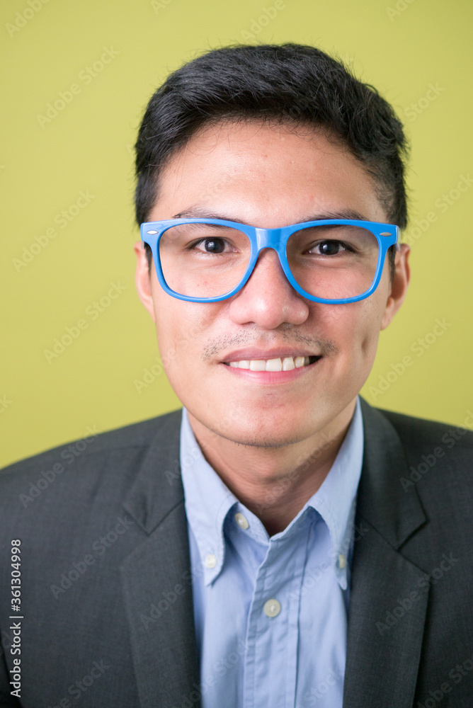 Face of happy young handsome Asian businessman with eyeglasses smiling