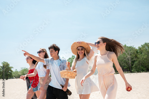 Walking down the beach. Seasonal feast at beach resort. Group of friends celebrating, resting, having fun in sunny summer day. Look happy and cheerful. Festive time, wellness, holiday, party.