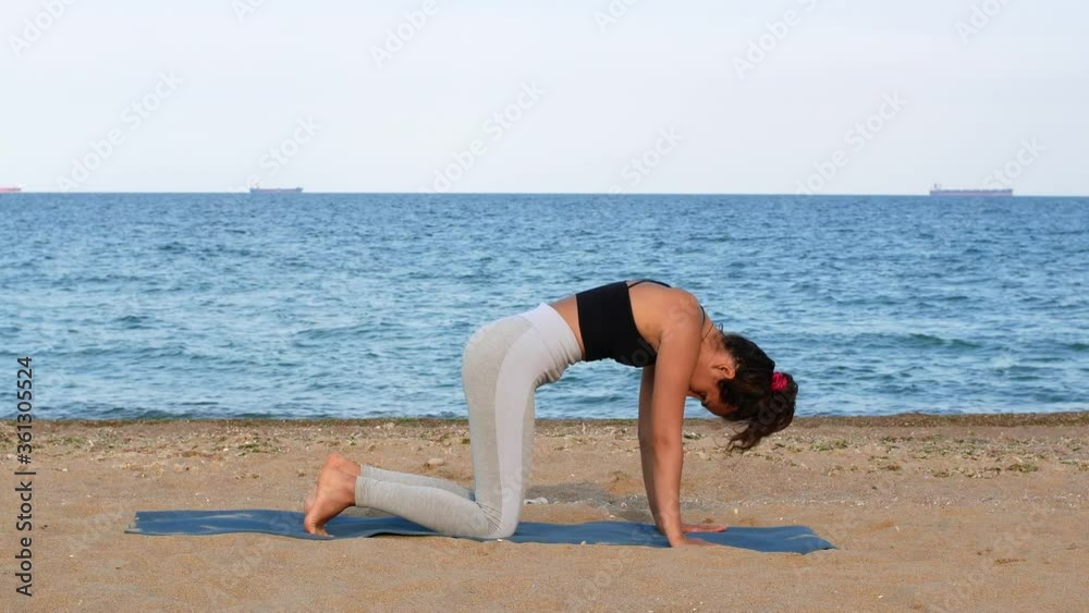 Athletic woman doing exercises on the beach near the sea. Athletic girl in sportswear pumps the abdominals. Sport, fitness and health. Close-up