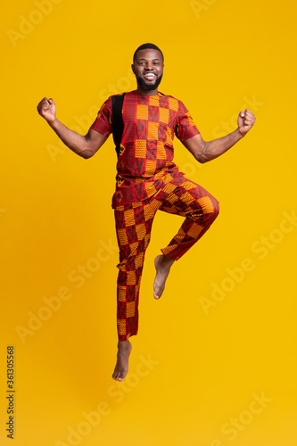 Excited black man jumping up over yellow background
