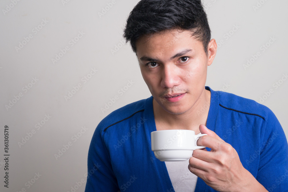 Portrait of young handsome Asian man drinking coffee Portrait of young handsome Asian man drinking coffee