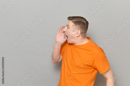 Excited man is shouting loudly in full voice with hand near mouth