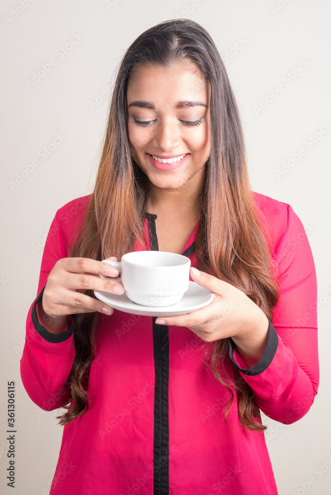 Φωτογραφία Portrait of happy young beautiful Indian businesswoman holding coffee cup