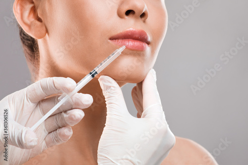 Lip injection for young woman, grey studio background