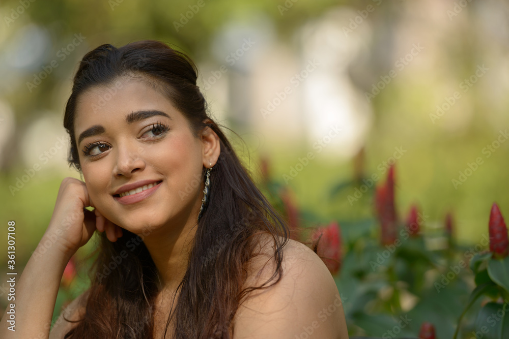 Face of happy young beautiful Indian woman thinking at the park Face of happy young beautiful Indian woman thinking at the park