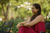 Profile view of happy young beautiful Indian woman sitting at the park