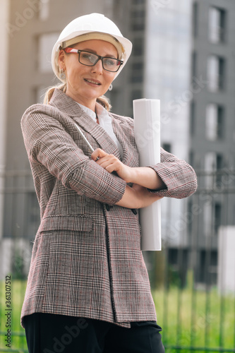 Stylish woman with glasses in uniform in a white helmet against the background of the business building. photo