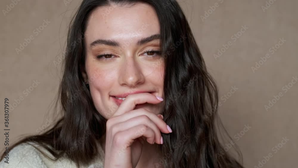 Close up view of Playful mystery pretty brunette woman posing and looking around over brown background Close up view of Playful mystery pretty brunette woman posing and looking around over brown background