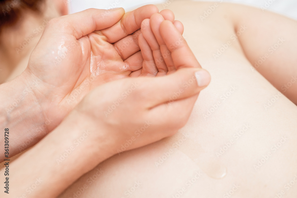 Massage oil in palms of massager while back massage of woman. Massage oil in palms of massager while back massage of woman.