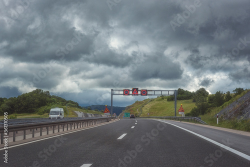 Picturesque highway in Croatia (autocesta A), the main automobile way with pointers and road signs. Scenic daytime landscape with fantastic clouds, shoot in motion