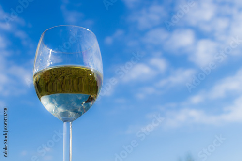 Fototapeta Naklejka Na Ścianę i Meble -  Kieliszek białego wina na tle niebieskiego nieba