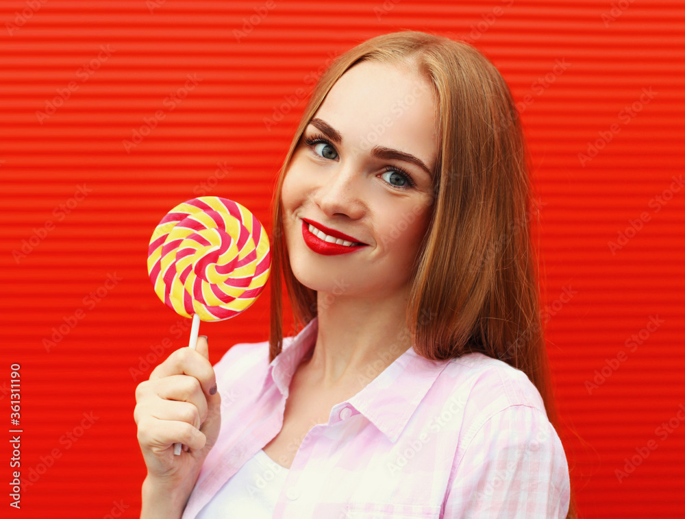 Portrait girl with lollipop on a red wall background