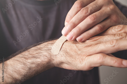 Man putting adhesive bandage on the hand.