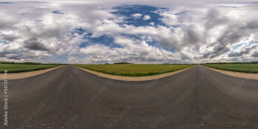 Fototapeta premium Full spherical seamless hdri panorama 360 degrees angle view on no traffic asphalt road among fields with cloudy sky in equirectangular projection, VR AR content