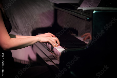 Girl playing grang piano in night club hands and keyboard photo