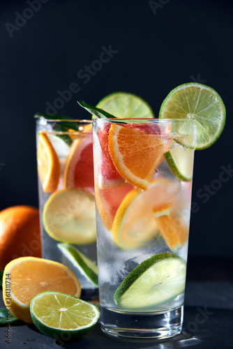 Health care, fitness, healthy nutrition diet concept. Fresh cool homemade citrus infused detox water with grapefruit, orange, lemon and lime and ice in glasses on dark background.