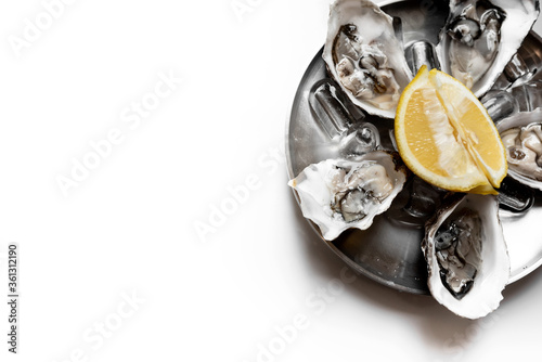 Fresh oysters close-up on plate, served table with oysters, lemon in restaurant. Gourmet food