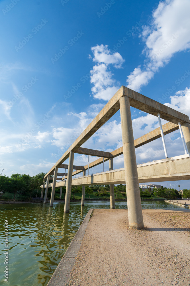 Angular view of concrete bridge over canal, with blue sky, in Juan Carlos I park in Madrid, Spain, vertically Angular view of concrete bridge over canal, with blue sky, in Juan Carlos I park in Madrid, Spain, vertically