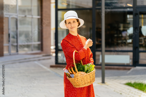 Young housewife vegan in red dress enjoying in shopping, walking at street after market. Lifestyle, consumerism, shopping, purchasing, selling, real, natural, healthy lifestyle concept.