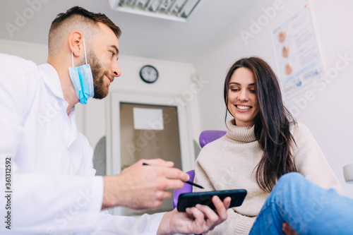 orthodontist holding phone with x-ray picture of jaw and showing