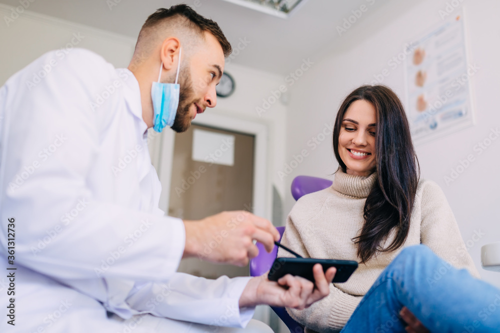Obraz premium Dentist showing teeth panoramic x-ray on phone. the female patie