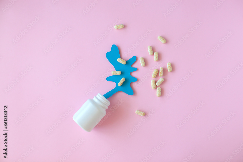 White pill packaging with blue paper splash on pink background. Medicine concept. White pill packaging with blue paper splash on pink background. Medicine concept.