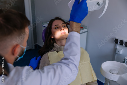 dentist working at dentist office  adjusting dental lamp  examin