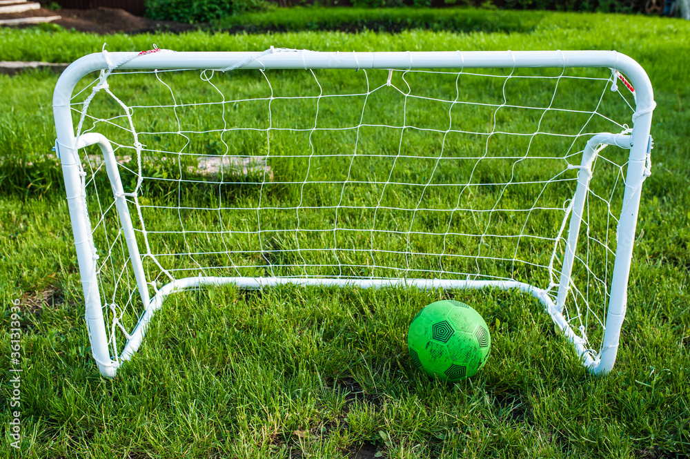 Green soccer ball and mini soccer goal on a green lawn on a home lawn Green soccer ball and mini soccer goal on a green lawn on a home lawn