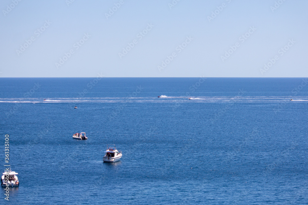 Boats and jetskis flying above the blue sea
