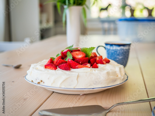 Swedish fika with a strawberry cake on wood table.