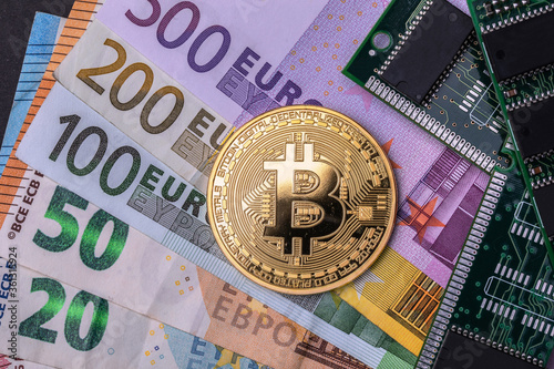 A bitcoin currency near the micro-schemes, all placed by several Euro banknotes. Top view. photo
