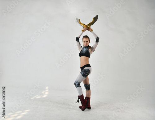 beautiful girl in a robot suit makes fighting movements with golden swords on a white background