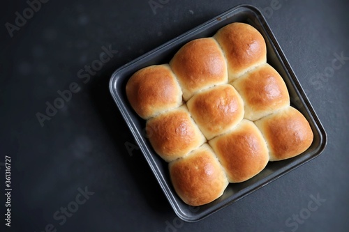 Freshly baked homemade Mumbai style golden Ladi pav or soft dinner bread roll in a baking tray. made out of all-purpose flour, yeast, milk and salt. Ideal for pav bhaji or missal pav. Copy space.